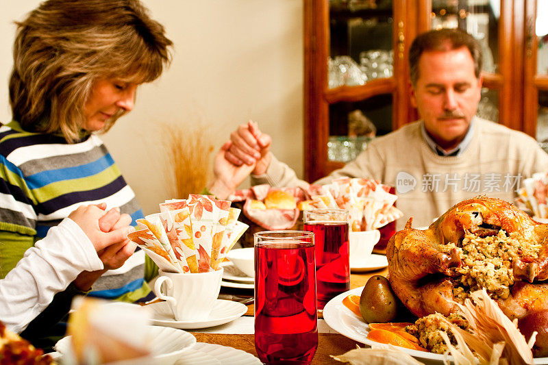男人和女人在感恩节晚餐上祈祷