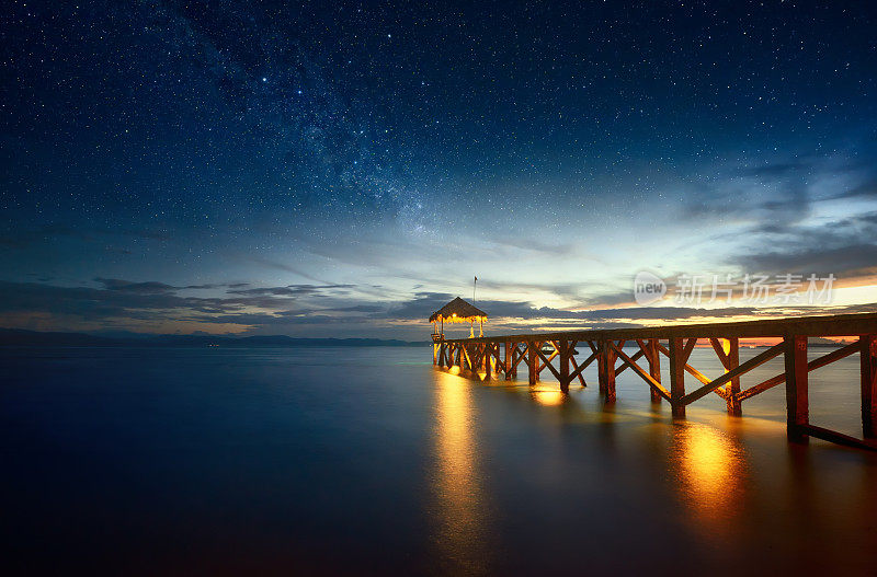 美丽的夜晚海景，银河的天空和码头延伸到海洋。