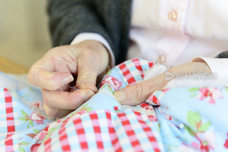 一位年长的妇女正在缝一床拼布被子
