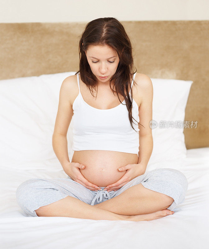 一个孕妇抱着肚子躺在床上
