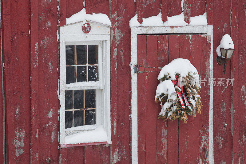 红色的谷仓门和旧的圣诞花环，雪