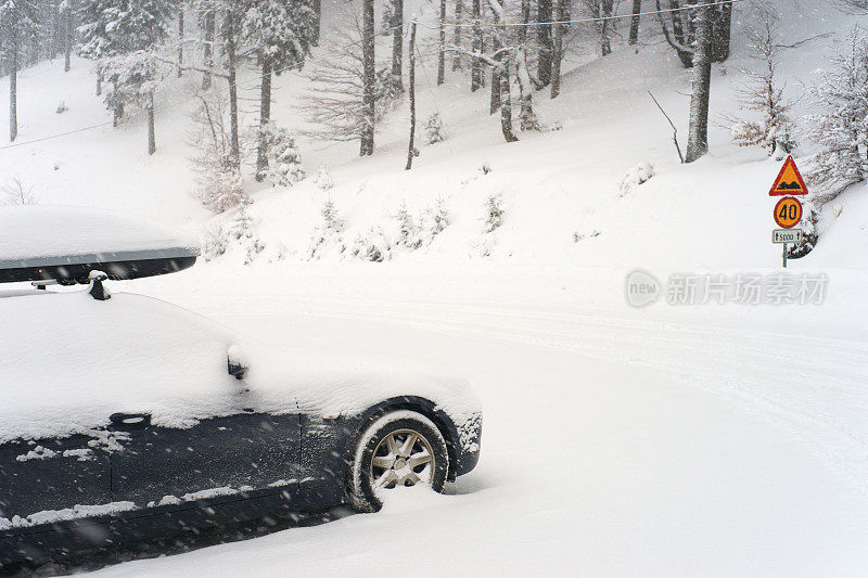 汽车被积雪覆盖在道路上。