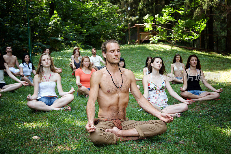 一大群人在野外冥想做瑜伽