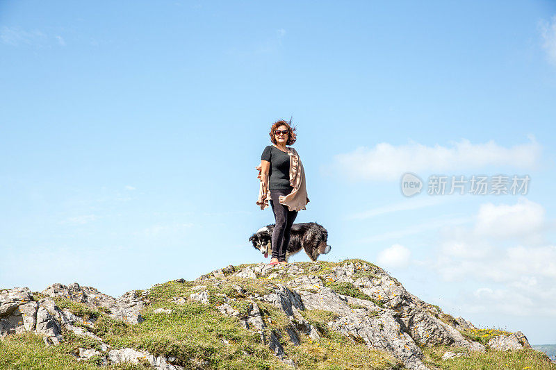 一个成熟的西班牙女人站在遥远的海岸岬角上