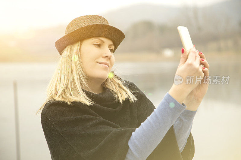 年轻女子在湖边与智能手机放松