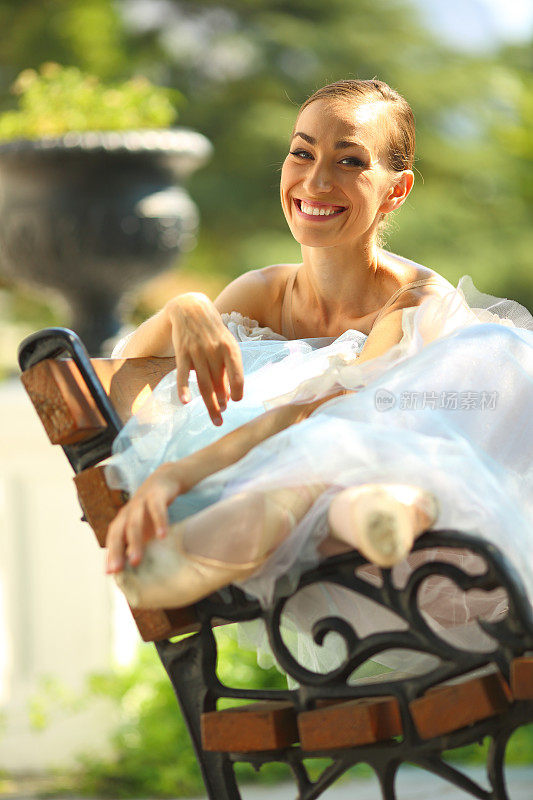 在公园长椅上微笑的芭蕾舞演员