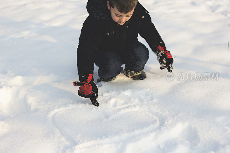 小男孩在雪地里画画