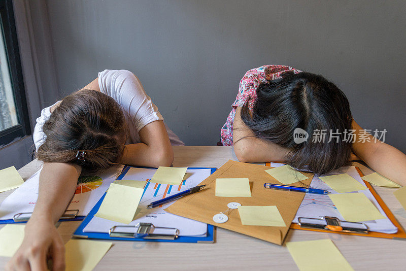 女人在桌上的文件和便利贴上睡着了