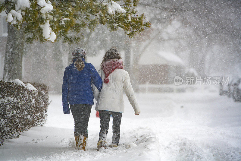 两个十几岁的女孩在下雪的街道上