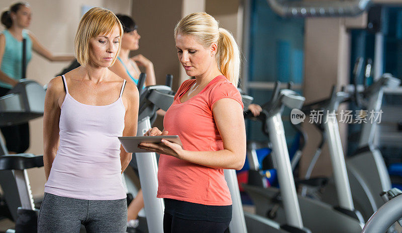 年轻女性在健身房有私人教练。