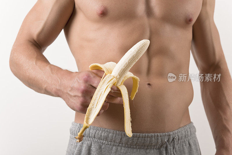 赤裸上身的肌肉男拿着剥了皮的香蕉