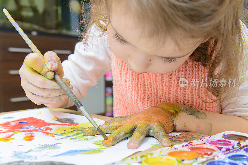 女孩在纸上和手上画颜料