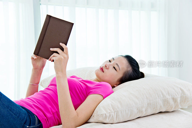 漂亮的年轻女子在家里看书