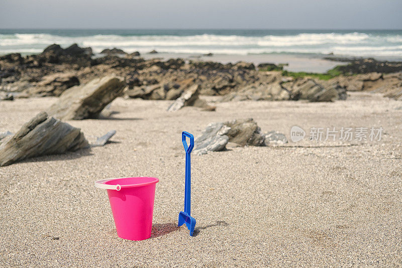 康沃尔纽基小费斯特海滩上的粉色桶和蓝色铲子。