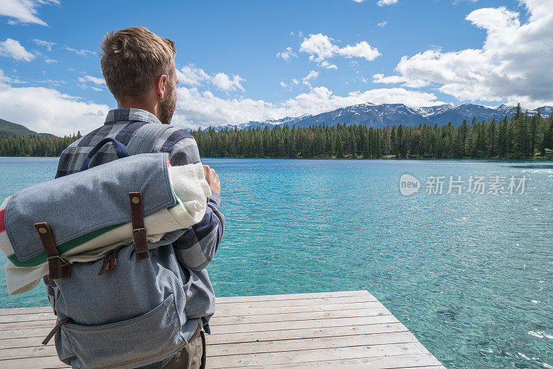 一个年轻人站在湖边的码头上看风景