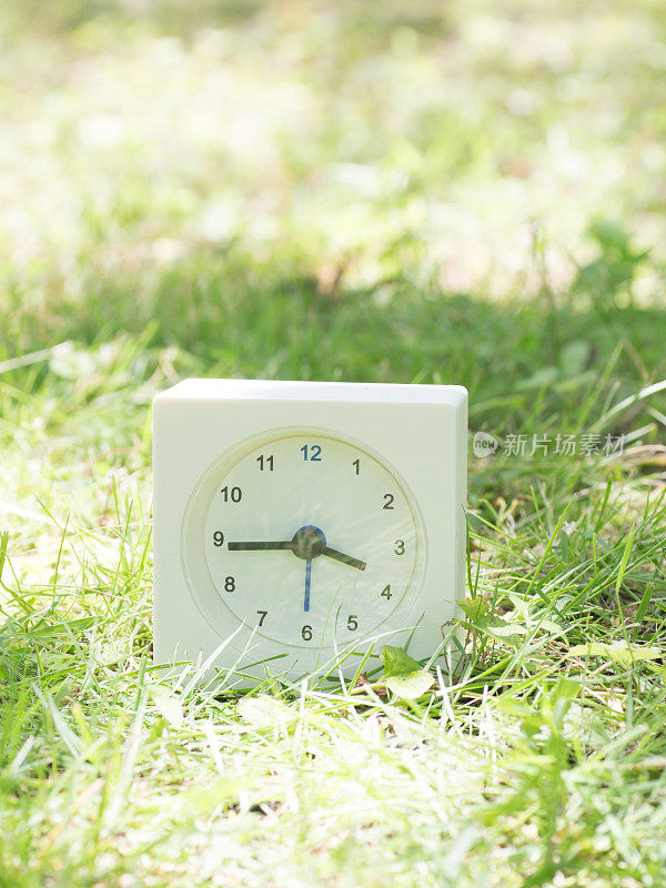 草坪上的白色简单时钟，3点45分，3点45分