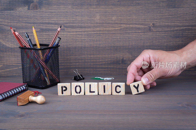 政策。黑色背景上的木制字母