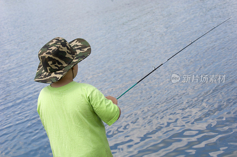男孩钓鱼在清澈，蓝色的湖。