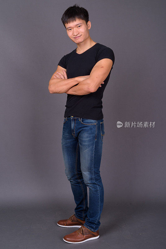 年轻的中国男子穿着黑色衬衫，映衬着灰色的背景
