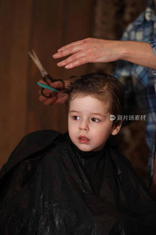 一个小男孩被美发师欢快的情绪迷住了