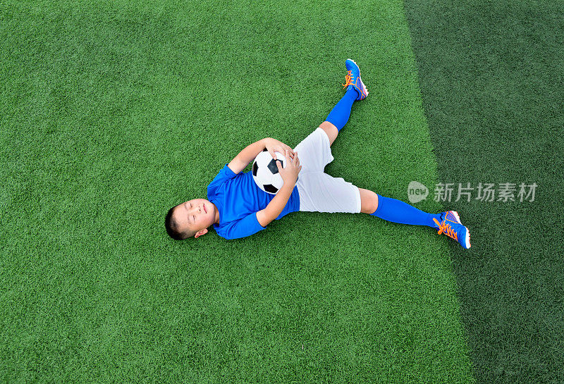小男孩躺在足球场上