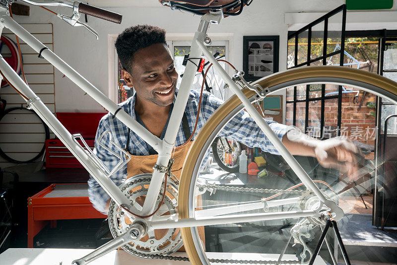 一名男子在自行车修理店旋转着车轮，检查着齿轮