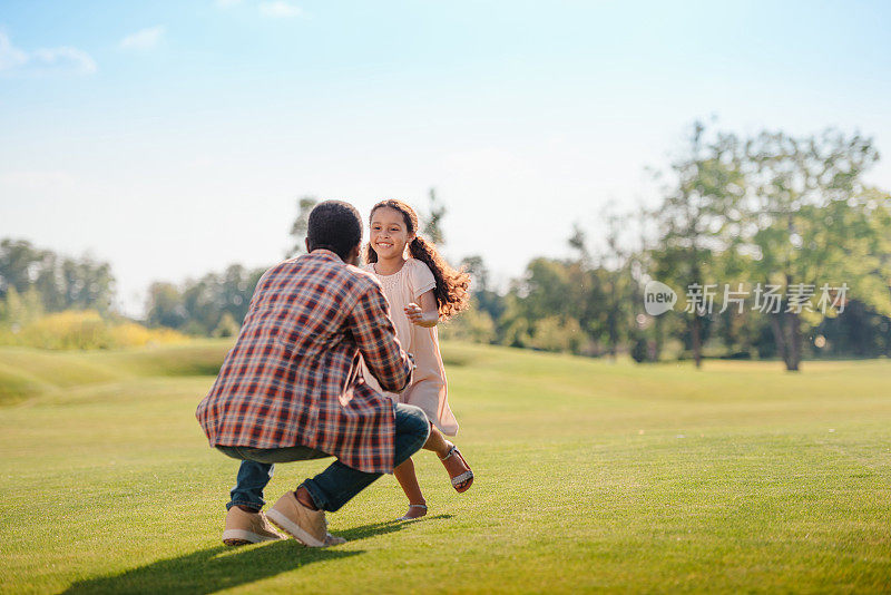 笑容可掬的非裔美国孙女在公园的草坪上跑向爷爷