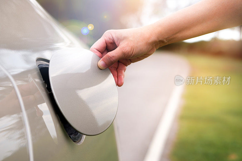 用手打开汽车的油盖加油。