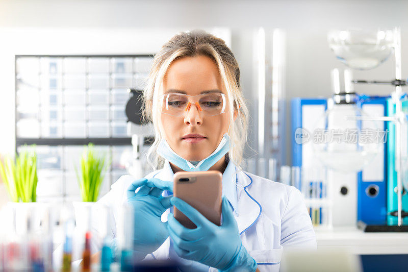 年轻迷人的女科学家在实验室里使用智能手机