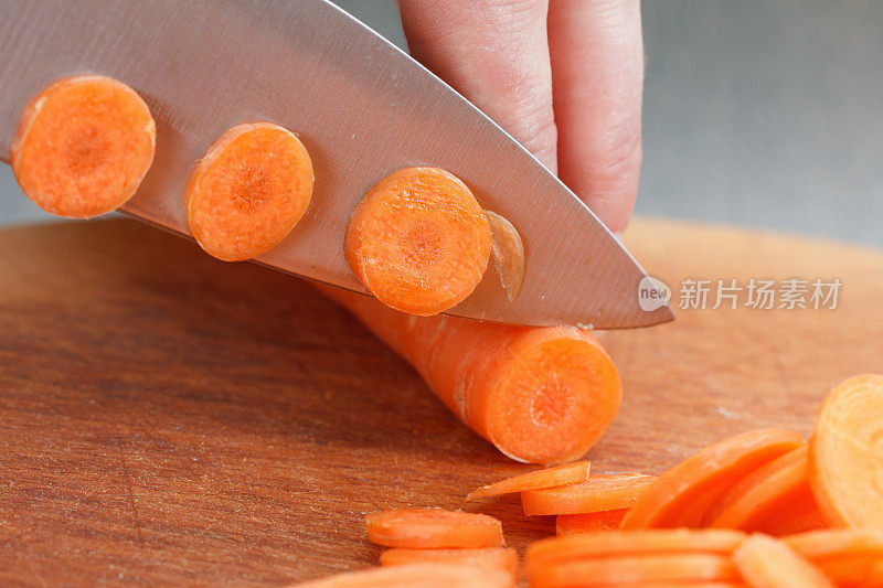 厨师用手在木板上切胡萝卜