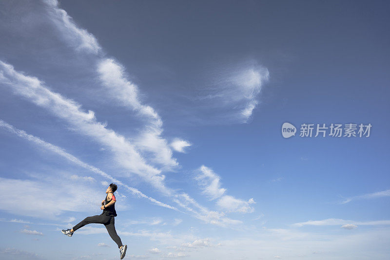 年轻的男运动员在柏油路上迎着天空奔跑