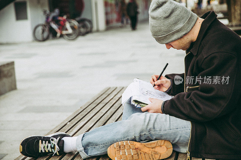 年轻的涂鸦艺术家在城市街道上素描