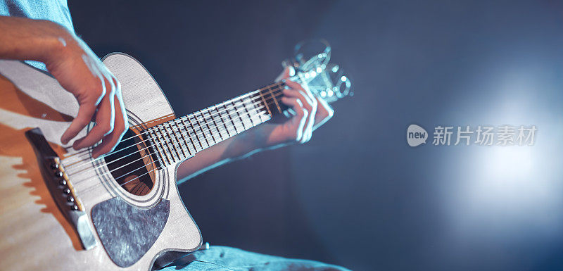 一个男人的手在弹原声吉他，特写，闪光，美丽的光在背景
