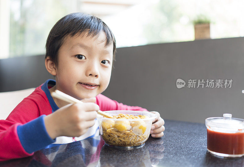 亚洲小孩用筷子吃美味的面条