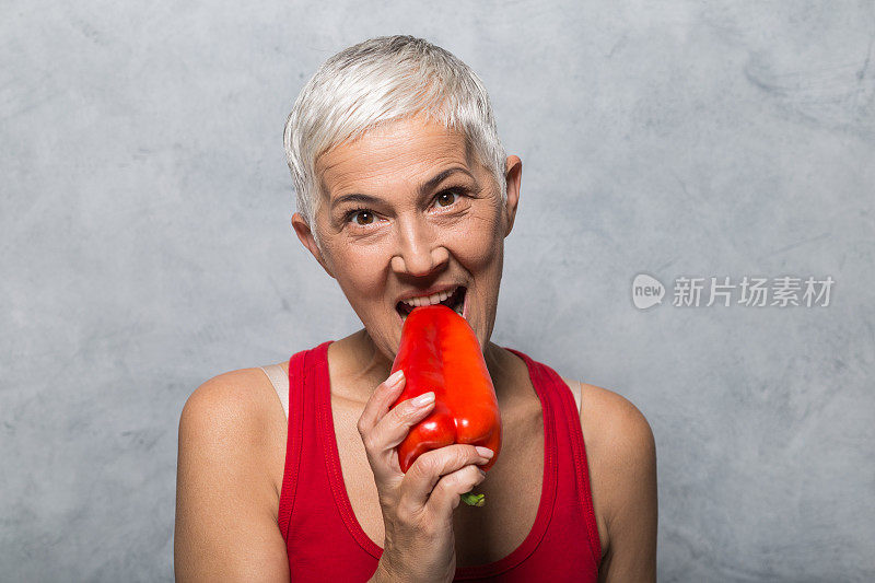 成熟的女人咬着红柿子椒