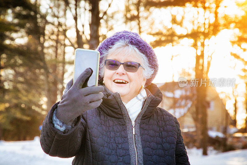 一位老年妇女在冬季散步时用手机自拍