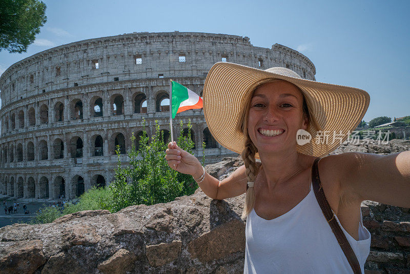 快乐的女人在罗马旅行，拿着意大利国旗自拍