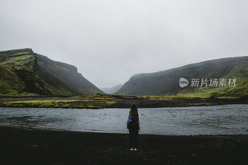 女人呆在冰岛高地美丽的湖和山附近