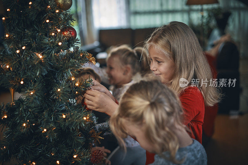 小女孩用装饰品和圣诞灯装饰圣诞树