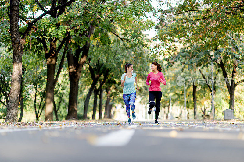 两个女性朋友在阳光公园的小路上慢跑