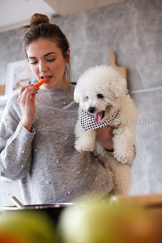 女孩吃胡萝卜，和她的狗做饭