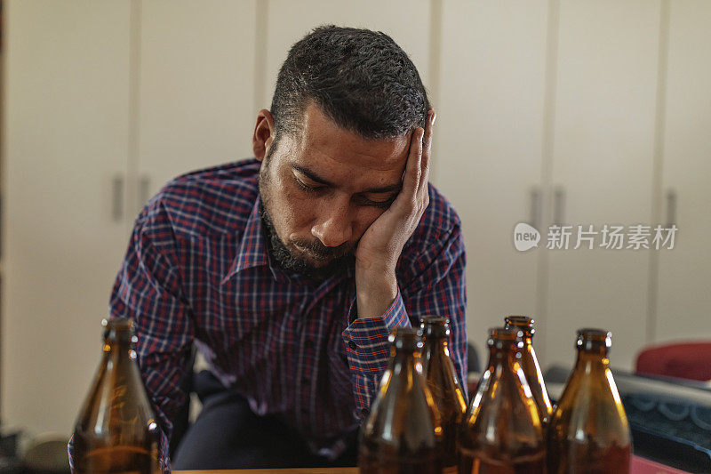 年轻悲伤的醉酒男子喝啤酒和酒精感到浪费，孤独和绝望的痛苦和情绪压力。人与酗酒、上瘾和男人抑郁的概念。