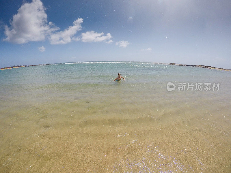 在天堂里游泳，孩子们在考艾岛的海洋里游泳，在荒芜的海滩上玩耍