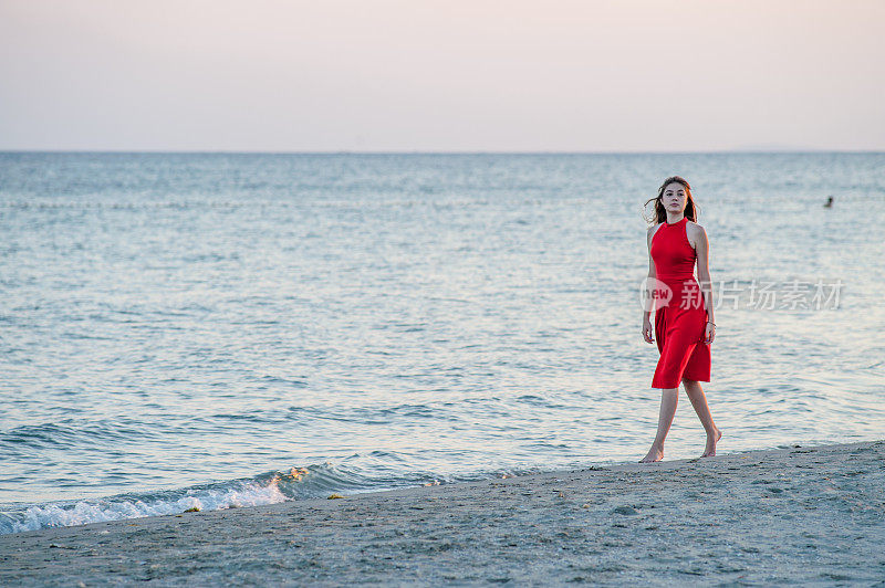 穿红衣服的年轻女子在海滩上跑步