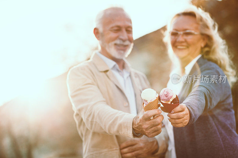 一对老年夫妇在一个阳光明媚的日子里吃着冰淇淋