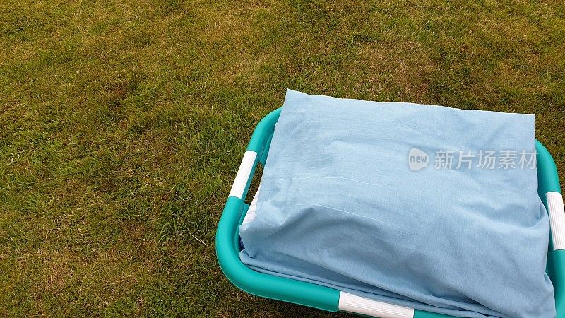 晾干的床单放在草地上的洗衣篮里