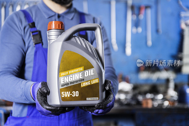 汽车修理工在汽车修理厂展示5W-30发动机油