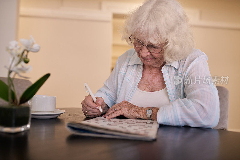 老女人在养老院的桌子上玩填字游戏