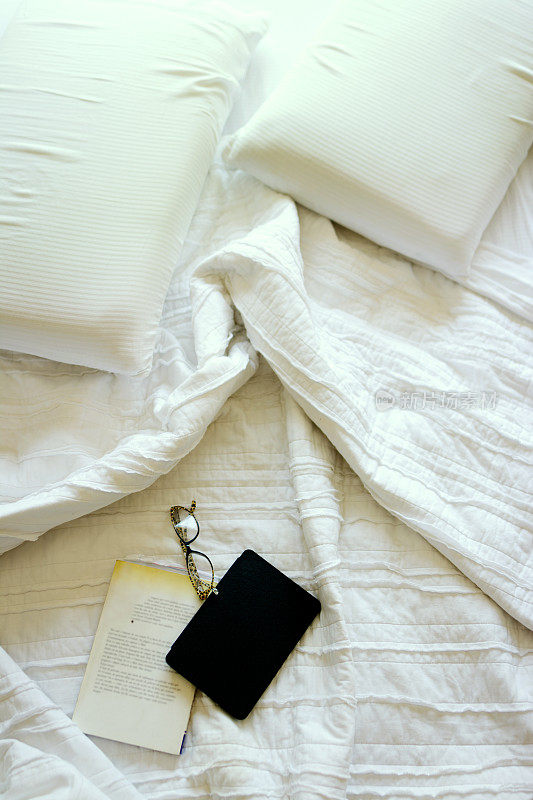 床上铺着床单，放着书和老花镜