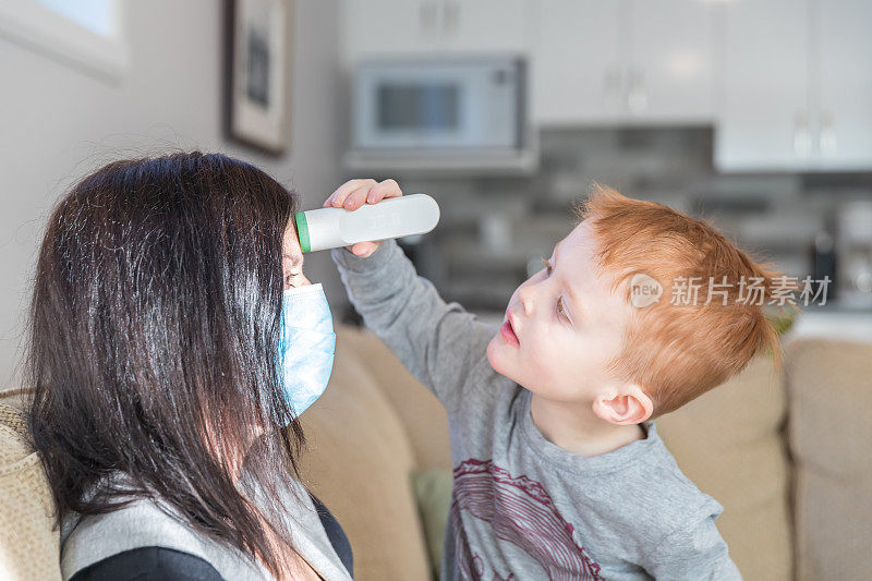 小男孩用红外温度计测量他生病的母亲的温度